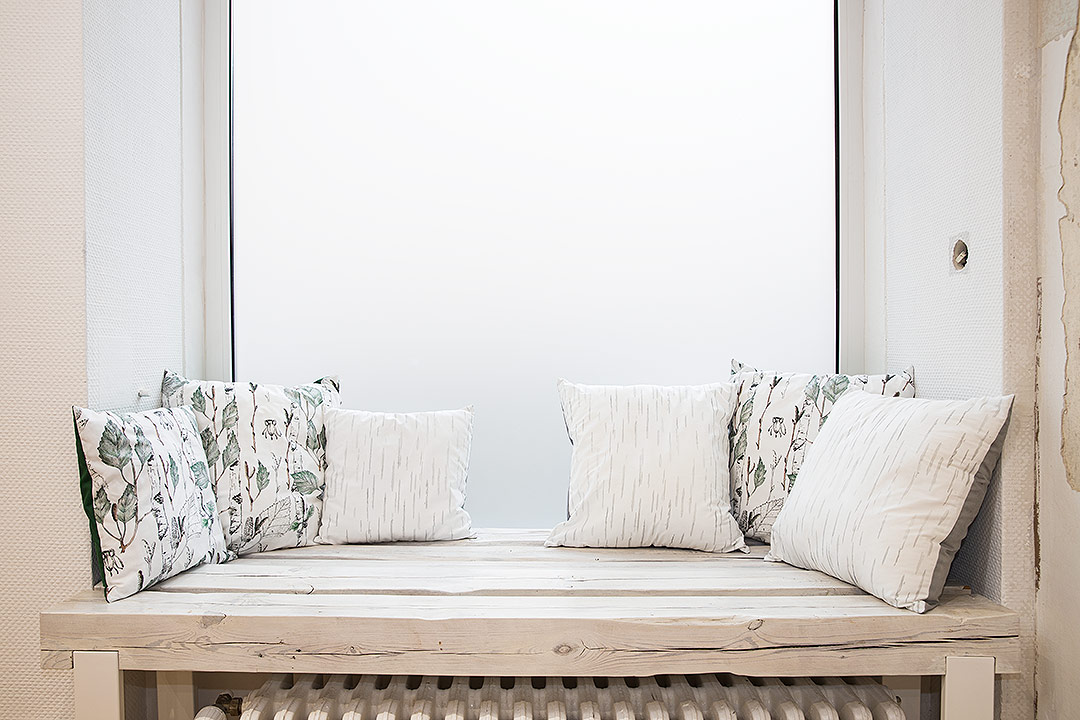 Weiße Holzbank mit Kissen in Birkenstoff